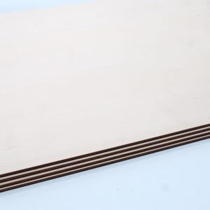 May include: Stack of four unfinished, light brown plywood sheets with a smooth surface.