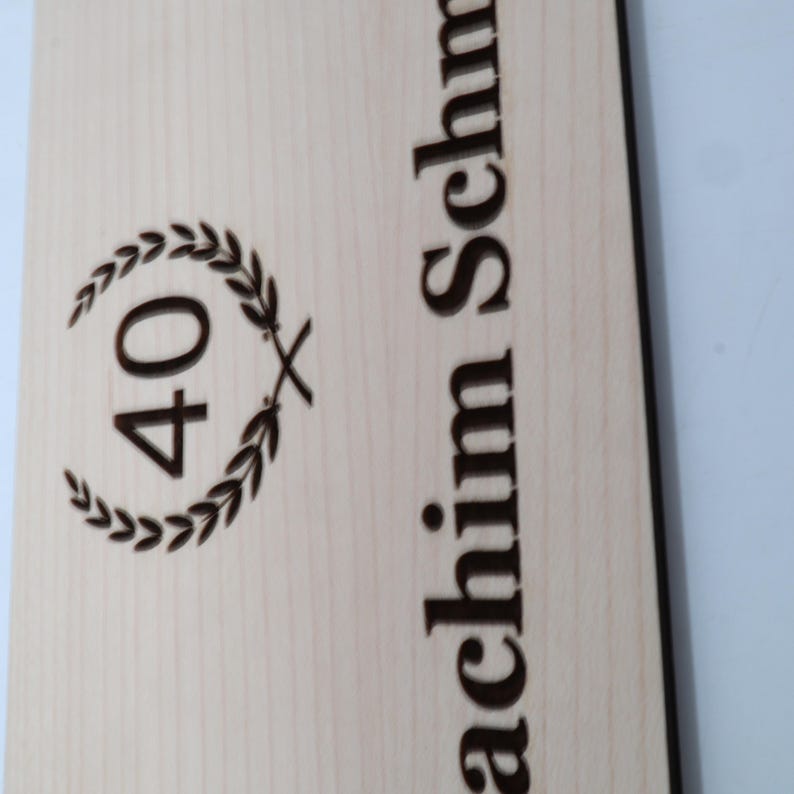 May include: A wooden plaque with the number 40 inside a laurel wreath and the text "achim Schm" below.