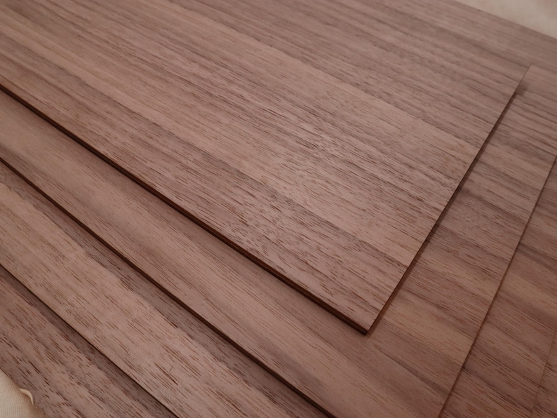 May include: Stacked sheets of light brown wood veneer. The wood grain is visible and has a natural, rustic look.