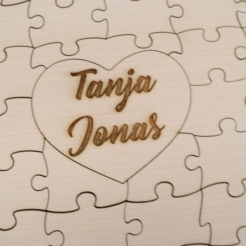 May include: A wooden jigsaw puzzle with a heart-shaped piece in the centre. The heart piece has the names "Tanja Jonas" engraved on it.