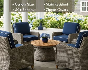 Könnte beinhalten: Vier Outdoor-Korbsessel mit marineblauen Kissen und weißem Paspel umrunden einen runden Holztisch. Der Text "Outdoor Cushions" steht oben, mit Details zu Sondergrößen, Fleckenbeständigkeit, über 50 Stoffen und Reißverschlussbezügen.