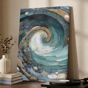 May include: An abstract canvas print of a swirling ocean wave. The artwork uses shades of blue, teal, and white, with textured brushstrokes. The wave is surrounded by a border of pebbles in various colours, creating a sense of depth and movement.