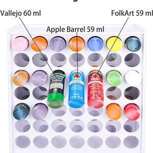 May include: White paint storage rack with 36 round holes for holding 60 ml bottles of paint. The rack is labeled with the text "Craft Paints Storage for 60 ml Bottles".  The rack is also labeled with the text "Vallejo 60 ml", "FolkArt 59 ml", and "Apple Barrel 59 ml".