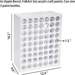 May include: White wooden paint bottle storage rack with 63 holes, measuring 16.2 inches tall, 12.4 inches wide, and 4 inches deep. Each hole is 1.5 inches in diameter.