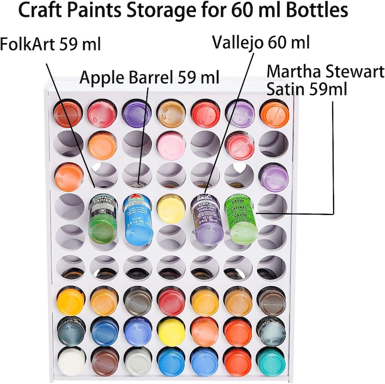 May include: White paint storage rack with 60 holes for 60 ml bottles. The rack is filled with various colors of paint bottles, including FolkArt, Vallejo, Apple Barrel, and Martha Stewart Satin.