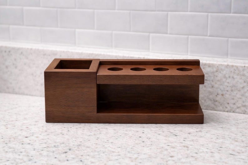 May include: A dark brown wooden desk organiser. It features a square compartment and a section with three circular holes. The organiser has a shelf underneath the holes and is made of solid wood. The unit is designed for desk organisation.