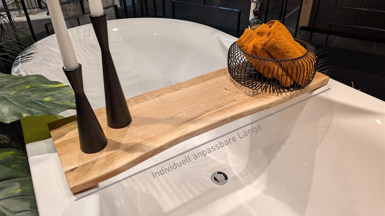 May include: A wooden bathtub tray with a natural finish, holding two black candle holders with white candles and a black wire basket filled with orange towels. The text "Individuell anpassbare L&auml;nge" is visible.