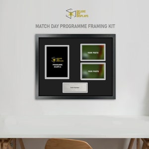 May include: A black framed Match Day Programme Framing Kit, designed to display a match day programme, two photos, and a text plate. The kit features the text "Match Day Programme Framing Kit" and the "Deluxe DIY Displays" logo. The program example is black with white text.