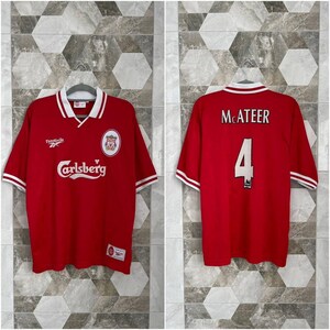 May include: Red Liverpool soccer jersey with white accents. Features the Carlsberg logo, Reebok logo, and a team crest. The back displays "McATEER" and the number "4".