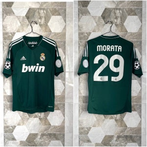 May include: A green soccer jersey with white accents. The jersey has the Adidas logo, the Real Madrid crest, and the text "bwin" on the front. The back of the jersey has the name "MORATA" and the number "29" in white.
