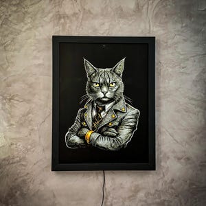 May include: Framed artwork featuring a distinguished cat in a gray suit with gold accents, a patterned tie, and crossed arms. The cat has intense yellow eyes and a serious expression. The artwork is set against a black background.