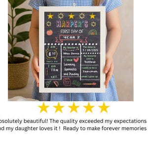 May include: A framed chalkboard sign with the text "HARPER'S FIRST DAY OF YEAR 2". The sign includes details like age, height, teacher's name, and favorite color. It is held by a person wearing a blue and white checkered dress.