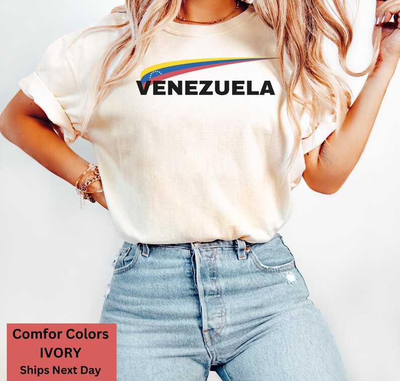May include: A white t-shirt with a graphic of the Venezuelan flag and the word "VENEZUELA" in black text.