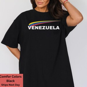 May include: Black t-shirt with a yellow, blue, and red graphic of the Venezuelan flag and the word "VENEZUELA" in white text.