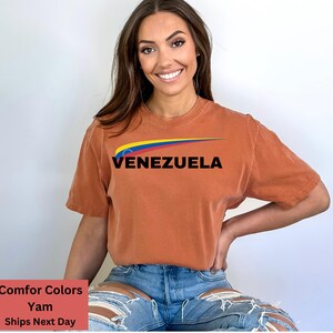 May include: A rust-colored t-shirt with a graphic of the Venezuelan flag and the word "VENEZUELA" in black text.