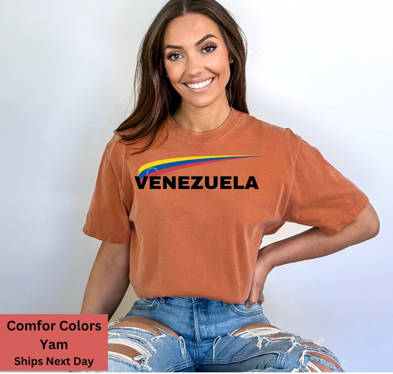 May include: A rust-colored t-shirt with a graphic of the Venezuelan flag and the word "VENEZUELA" in black text.