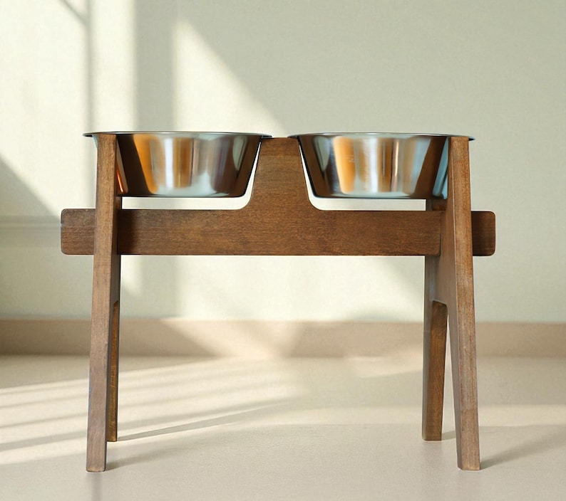 May include: A wooden pet feeder with two stainless steel bowls. The feeder is made of dark brown wood and has a simple, modern design. The bowls are elevated, making it easier for pets to eat and drink. The feeder is suitable for cats and dogs.