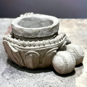 May include: A gray ceramic planter shaped like a baseball mitt with two baseballs on the side.