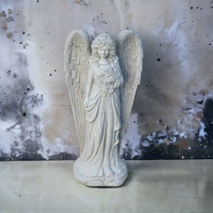 Tall angel with flowers in hands statue Concrete religious figure Standing girl in dress sculpture