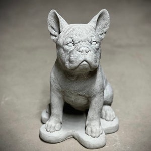 May include: A gray concrete statue of a French bulldog sitting on a base. The statue is detailed with realistic features, including the dog's wrinkles and ears.