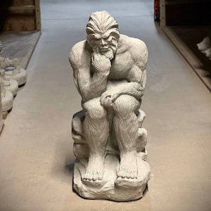 Large Bigfoot sitting on stone statue Huge snowman on rock figure Thinking Bigfoot outdoor sculpture