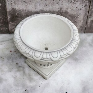 May include: White ceramic planter with a decorative, scalloped rim and a round base. The planter is empty and ready for planting.