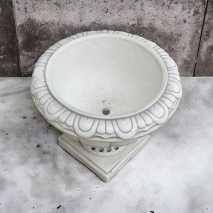 May include: White ceramic planter with a decorative, scalloped rim and a round base. The planter is empty and ready for planting.