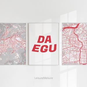 May include: Three framed prints with a white background. Two prints feature red city maps on a gray background. The center print has the red text "DA EGU". The bottom of the image has the text "LeisureMeisure".