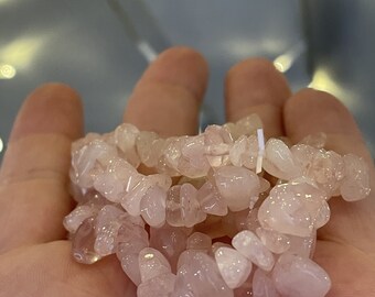 May include: A pink rose quartz chip bracelet with a natural, tumbled finish. The bracelet is made of small, irregular shaped chips of rose quartz.