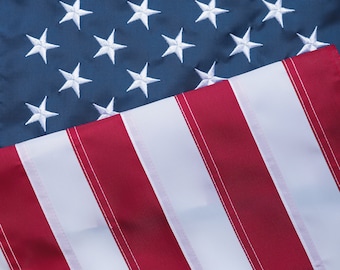 May include: A close-up of an American flag with red and white stripes and blue field of stars. The flag is folded in half, with the stars visible on the top half and the stripes visible on the bottom half.
