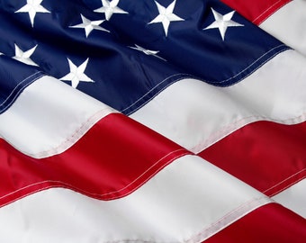 May include: A close-up of a folded American flag, showing the red and white stripes and the blue field with white stars. The fabric is textured and the seams are visible.