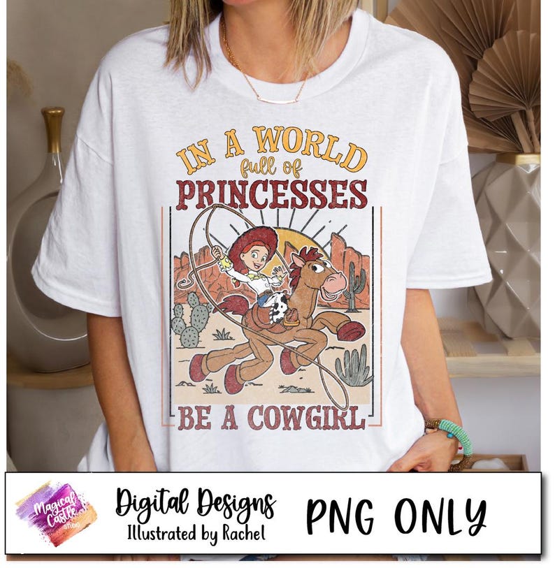 May include: A white t-shirt with a vintage-style graphic featuring a cartoon cowgirl riding a horse. The text reads "In a world full of princesses, be a cowgirl".