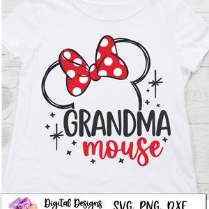 May include: A white t-shirt with a black and red design. The design features a black outline of Mickey Mouse's ears with a red bow with white polka dots. The text "Grandma Mouse" is written in black and red below the ears.