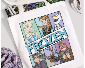 Może przedstawiać: Biała torba typu tote z kolorową grafiką postaci z filmu Kraina Lodu. Grafika zawiera Elsę, Annę, Olafa, Kristoffa, Svena i napis "FROZEN".