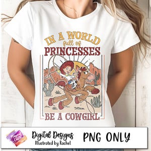 May include: A white t-shirt with a vintage-style graphic featuring a cartoon cowgirl riding a horse. The text reads "In a world full of princesses, be a cowgirl".
