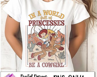May include: A white t-shirt with a vintage-style graphic featuring a cartoon cowgirl riding a horse. The text reads "In a world full of princesses, be a cowgirl".
