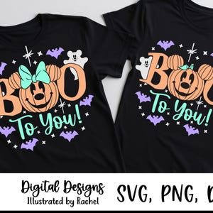 Può includere: Due magliette nere con un design grafico che riporta il testo "BOO To You!" in color pesca e turchese. Il disegno include una zucca con orecchie da topo, un fiocco turchese, fantasmi bianchi e pipistrelli viola, circondati da stelline.