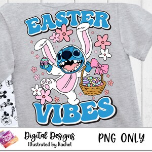 Puede incluir: Una camiseta gris con un dise&ntilde;o de conejo de Pascua azul y blanco. El conejo sostiene una cesta de huevos de Pascua y tiene una cara de personaje Stitch azul. El texto "Easter Vibes" est&aacute; en letras azules y blancas.