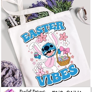 May include: A white tote bag with a blue and pink Easter themed design featuring Stitch from Lilo & Stitch dressed as an Easter bunny. The text "Easter Vibes" is written in blue letters.