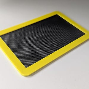 May include: A yellow plastic frame with a black mesh screen inside.