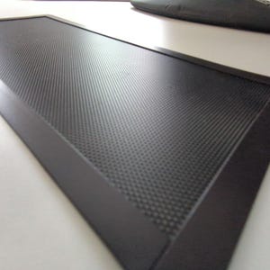 Pu&ograve; includere: Una griglia di ventilazione rettangolare nera con un motivo a griglia a maglia fine. La griglia &egrave; circondata da una cornice nera.