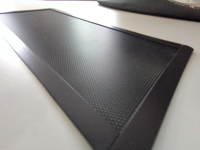Pu&ograve; includere: Una griglia di ventilazione rettangolare nera con un motivo a griglia a maglia fine. La griglia &egrave; circondata da una cornice nera.
