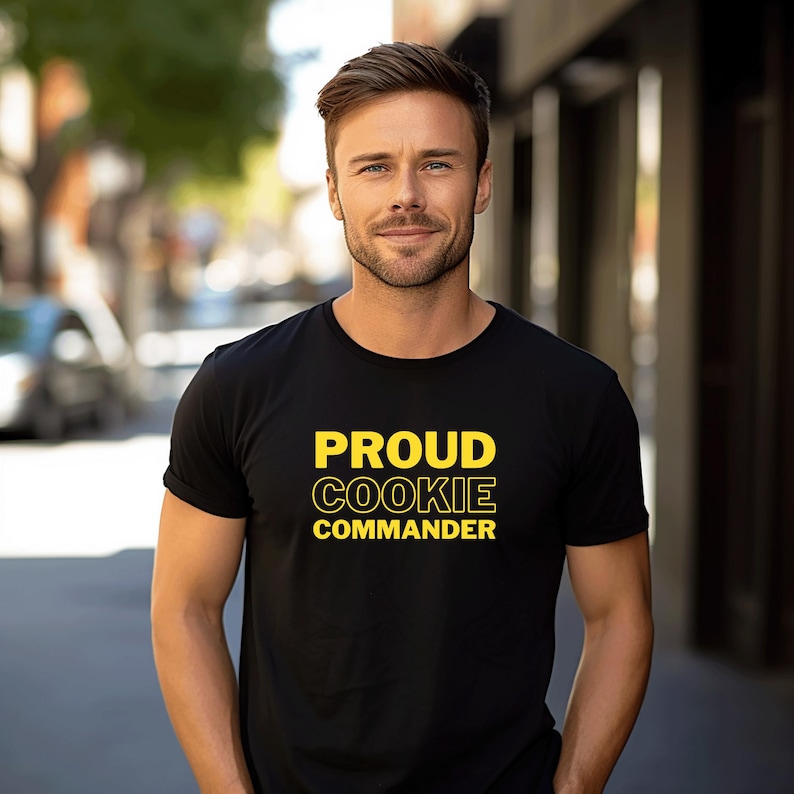 May include: A black t-shirt with the text "PROUD COOKIE COMMANDER" in yellow.