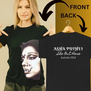 May include: Black t-shirt with a white graphic print of a woman's face on the front and the text "ASHA PUTHLI She Out Here Australia 2024" on the back.