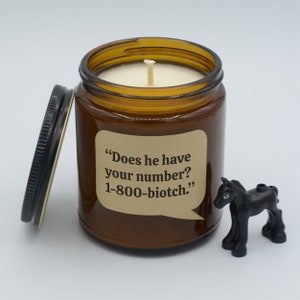 May include: A brown glass candle jar with a white candle and a label that reads "Does he have your number? 1-800-biotch."