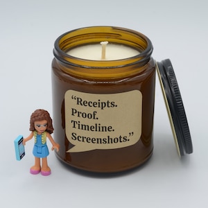 May include: A brown glass candle jar with a beige label that reads "Receipts. Proof. Timeline. Screenshots." The candle is lit and the lid is off to the side.