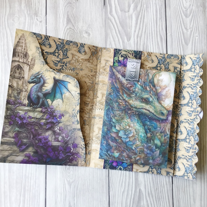May include: A decorative journal with a blue dragon design on the front cover. The journal has a silver metal clasp and a floral design on the back cover.