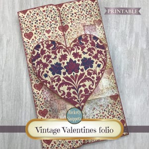 May include: A vintage Valentine's folio with a large heart-shaped design. The heart features a floral pattern in burgundy and navy blue, set against a cream background. The folio is decorated with hearts and floral motifs. The text "Vintage Valentines folio" is displayed.