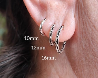 May include: Three silver hoop earrings in different sizes, 10mm, 12mm, and 16mm, worn in a person's earlobe.