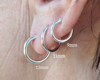 May include: Three silver hoop earrings of different sizes, 9mm, 11mm, and 13mm, shown on a person's ear.